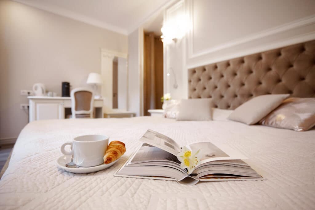 Hotelska soba. Na postelji kavna skodelica in rogliček.