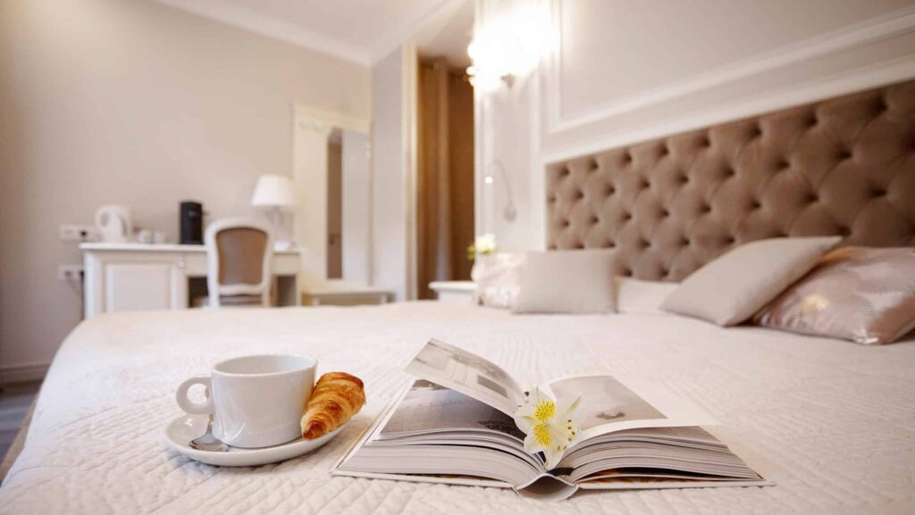 Hotelska soba. Na postelji kavna skodelica in rogliček.