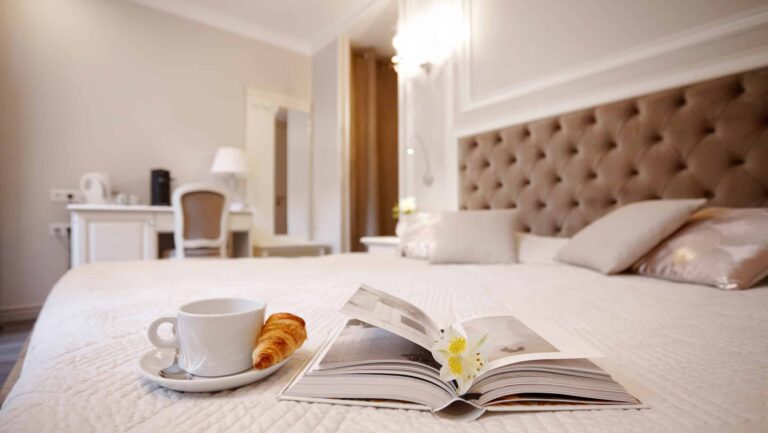 Hotelska soba. Na postelji kavna skodelica in rogliček.