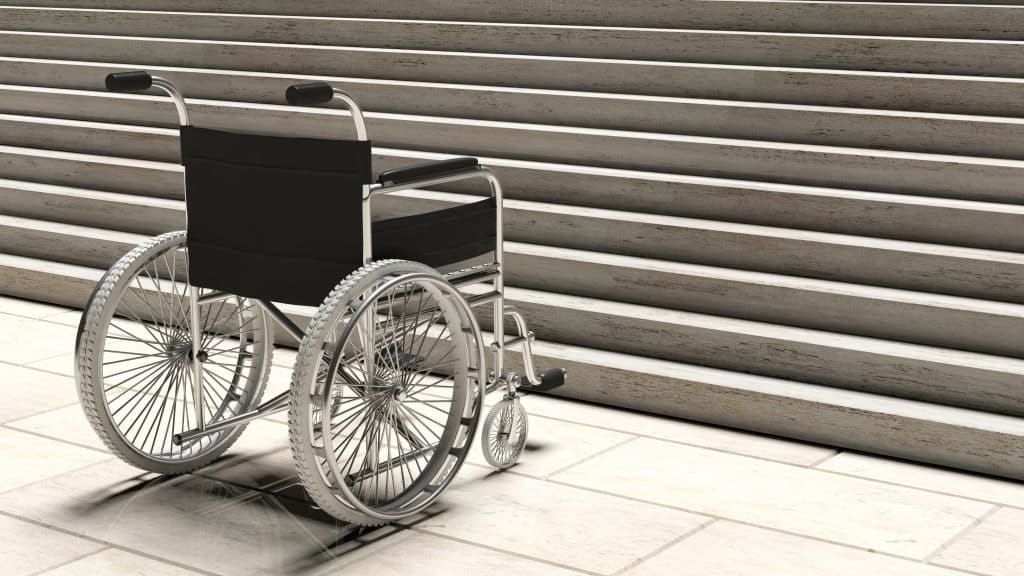 Simbolična fotografija invalidskega vozišča pred stopniščem.