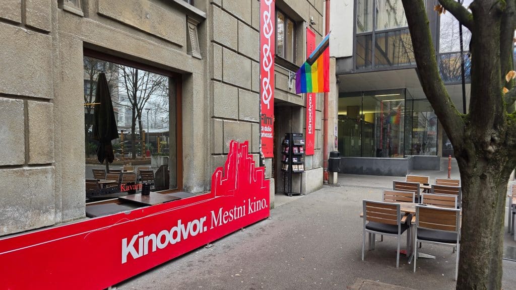 Kinodvor. Na vrati visi mavrična zastava.