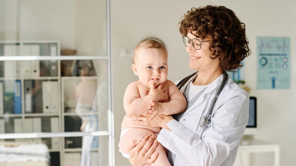 Simobolna fotografija pediatrinje, ki v naročju drži otroka.