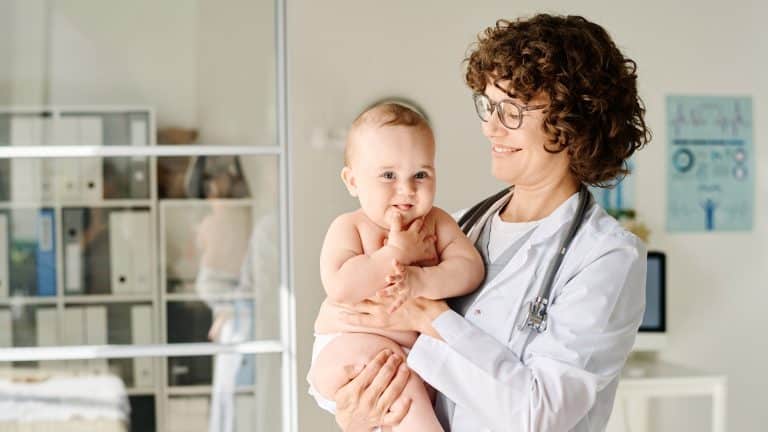 Simobolna fotografija pediatrinje, ki v naročju drži otroka.