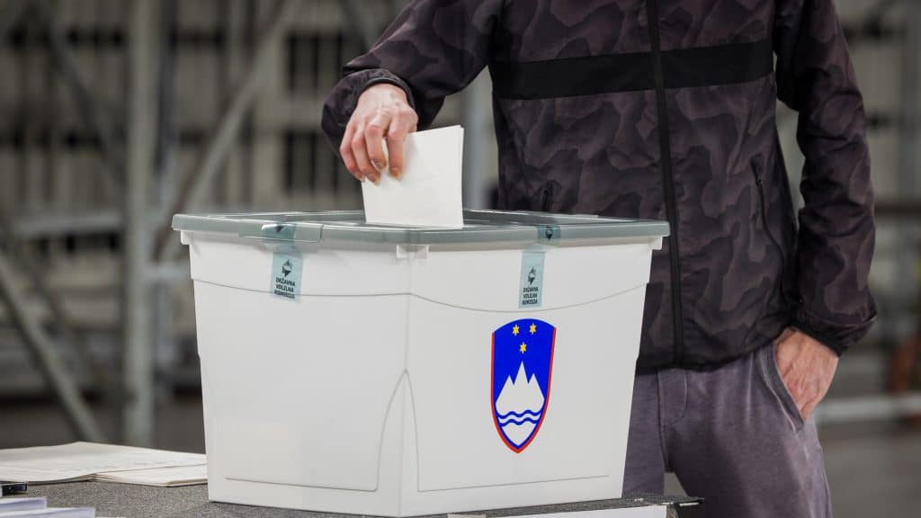 Oseba oddaja svoj glas na državnozborskih volitvah v volilno skrinjico.