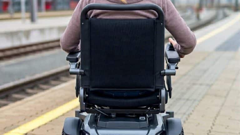 Slika osebe na invalidskem vozičku na železniški postaji